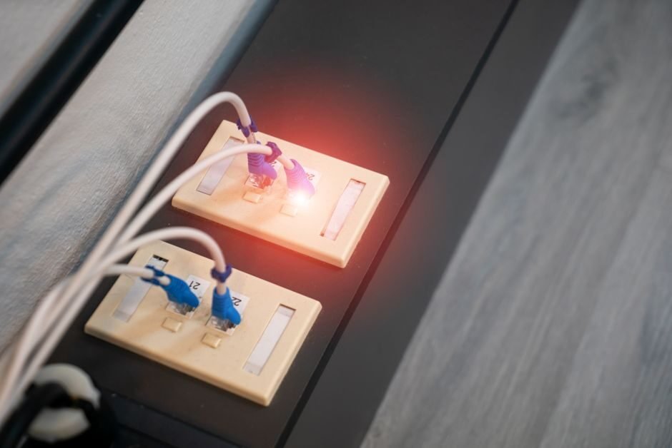 Close-up of Ethernet wall jacks with cables connected and an illuminated indicator light