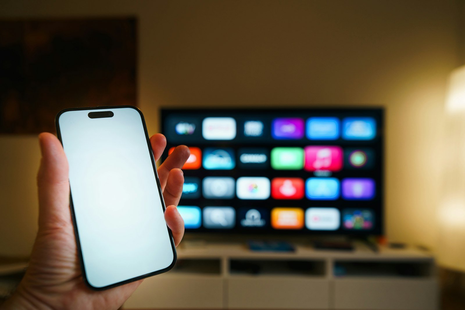 Smartphone held in front of a smart TV, illustrating mobile versus desktop bandwidth testing