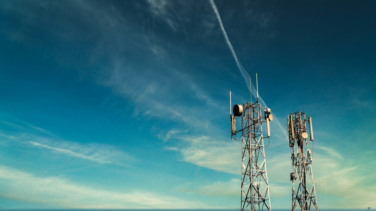 Metal cell tower under a blue sky, the ground coverage that satellite to phone service backs up in dead zones