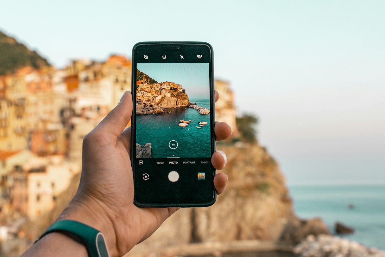 Person holding a phone near a cliff, where satellite to phone service can send a text